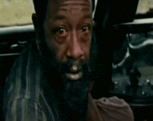 a man with a beard is sitting in a car with his eyes closed .