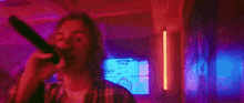 a man is singing into a microphone in a dark room with red and blue lights .