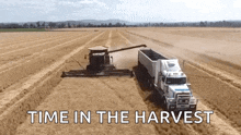 an aerial view of a combine harvester and a truck in a field with the words time in the harvest