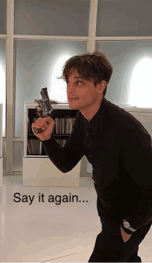 a man is holding a gun in front of a sign that says " say it again "