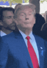a man in a blue suit and red tie looks up at something