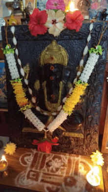 a statue of ganesha is surrounded by garlands of flowers and candles