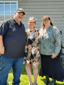 a man and two women pose for a picture in front of a building