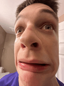 a close up of a man 's face with a purple shirt on