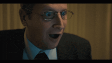 a close up of a man wearing glasses with his mouth open