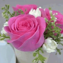 a bouquet of pink roses and white flowers in a white vase .