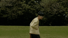 a man in a yellow jacket is standing in a field with his mouth open .