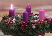 a christmas wreath with four purple candles and decorations