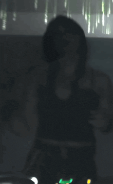 a blurred image of a woman in a dark room with a green light behind her