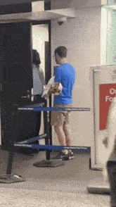 a man in a blue shirt is standing in front of a barrier that says united states postal service on it