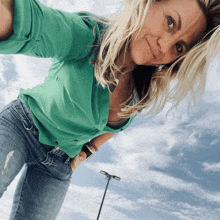 a woman wearing a green shirt and blue jeans smiles