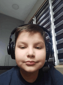 a young boy wearing headphones looks at the camera