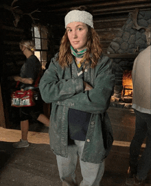 a woman standing with her arms crossed wearing a green jacket