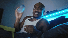 a man in a white tank top is holding a plastic bottle in his hand