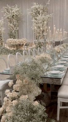 a long table with plates , candles , flowers and baby 's breath on it .