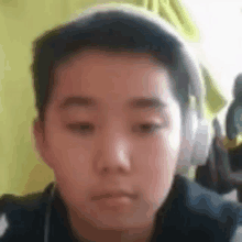 a young boy wearing headphones is looking at the camera and making a funny face .