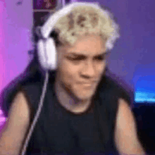 a man wearing headphones and a black shirt is sitting in front of a computer .