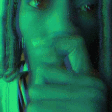 a close up of a woman 's face with a green background behind her