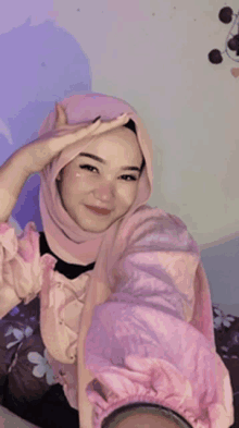 a woman wearing a pink hijab is taking a picture of herself