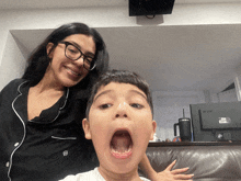 a woman stands next to a boy with his mouth open and an acer monitor in the background