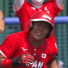 a baseball player wearing a red jersey and a red hat with the word japan on it is smiling .