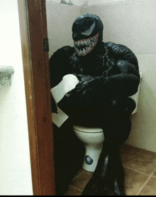 a man in a venom costume sits on a toilet