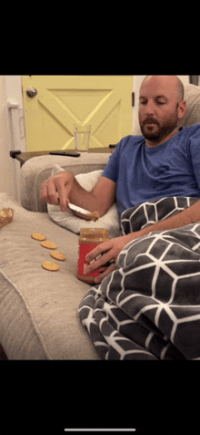 a man is sitting on a couch eating peanut butter