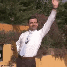 a man in a white shirt and tie is standing with his arm in the air .