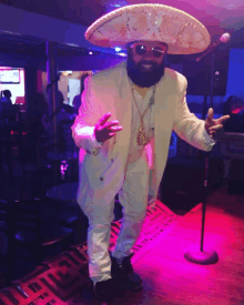 a man with a beard wearing a sombrero and sunglasses stands in front of a microphone