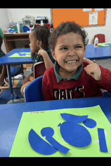 a young boy wearing a red shirt that says dad 's is making a face