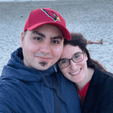 a man wearing a red cardinals hat stands next to a woman