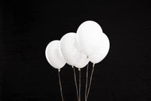 a bunch of white balloons against a black backdrop