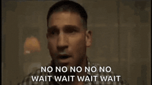 a man in a plaid shirt is standing in a dark room and says no no no no no wait wait wait wait .