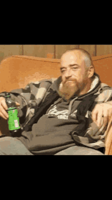 a man sitting on a couch holding a bottle of soda