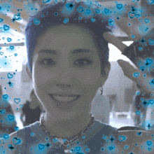 a woman with short blue hair is smiling with blue hearts and stars surrounding her