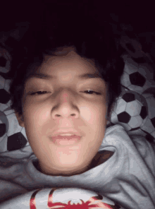 a young boy laying on a bed with soccer balls on it