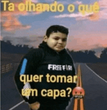 a boy is standing on a highway wearing a free fire sweatshirt .