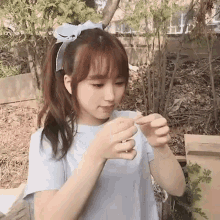 a young girl wearing a headband and a white shirt is holding a piece of paper in her hands .