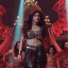 a woman in a crop top is dancing on a stage with other women