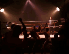 a referee stands in the middle of a wrestling ring watching two men fight