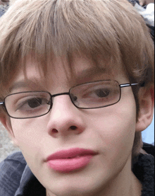 a close up of a young boy wearing glasses and pink lipstick