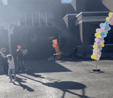 a bunch of balloons are hanging from a pole in a courtyard