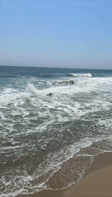 waves crashing against a sandy beach on a clear day