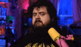 a man with a beard is sitting in front of a pink microphone .