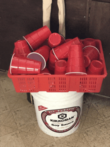 a bucket of kikkoman soy sauce sits on a tiled floor