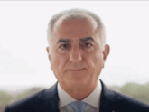 a man in a suit and tie looks at the camera with a serious look on his face