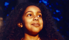 a young girl with long curly hair is looking up at the sky in a close up of her face .