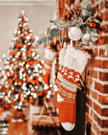 christmas stockings are hanging on a brick fireplace next to a christmas tree