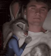 a man is laying in bed with a stuffed bunny rabbit .