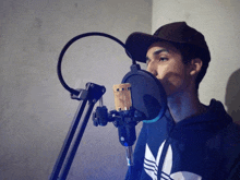 a man singing into a microphone wearing an adidas hoodie